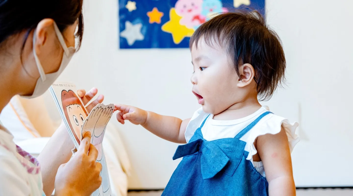 子供が絵本を指さしている画像