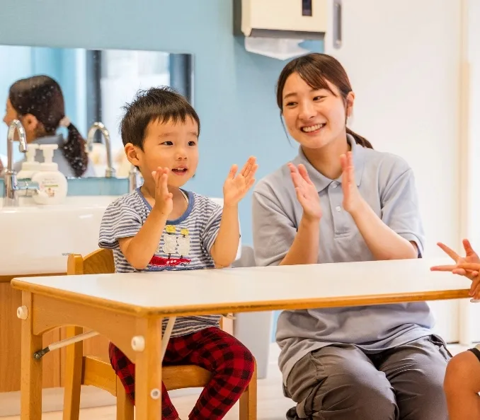 子供と先生が手拍子をしている画像